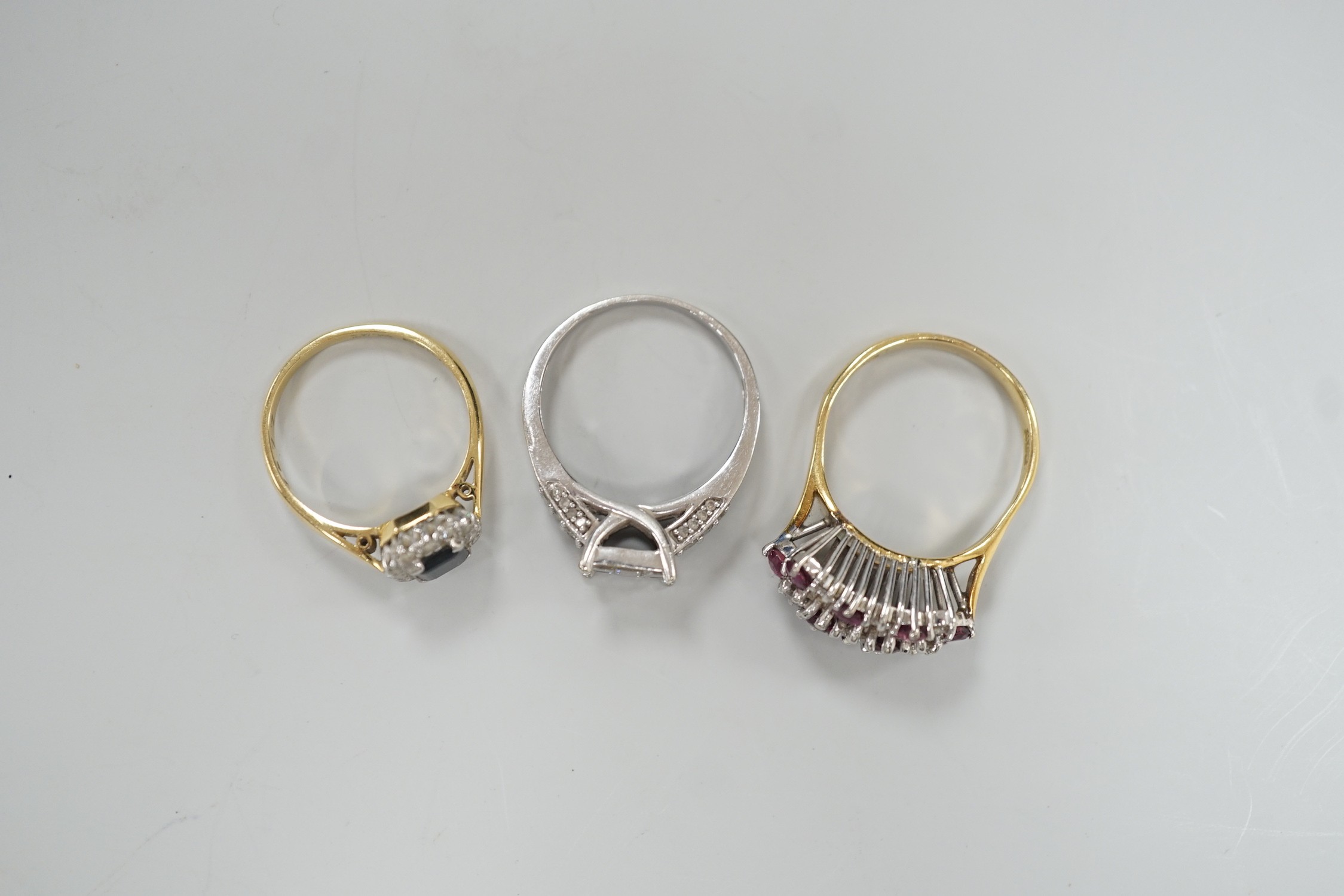 Three assorted modern gem set rings, including white metal and diamond cluster tablet ring with diamond set shoulders, an 18ct gold, sapphire and diamond cluster set ring and an 18ct gold ruby and diamond set cluster rin